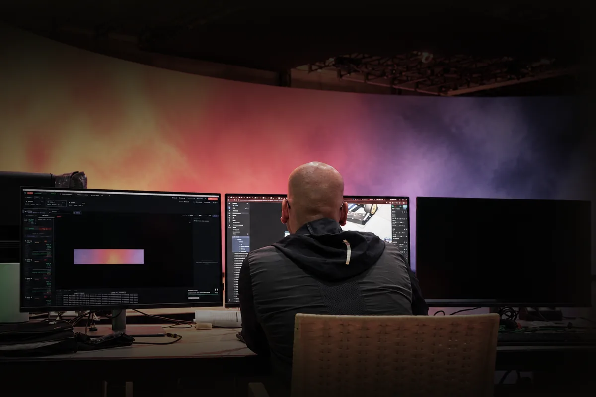Operator at a multi-monitor control station in front of the LED wall